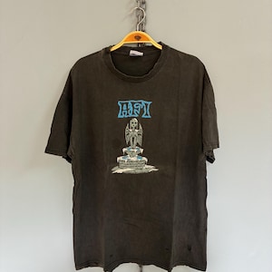 May include: Dark gray t-shirt with the band name "AFI" in blue block letters above a graphic of a statue on a tiered fountain. The shirt has a distressed look, with small holes and a faded appearance.