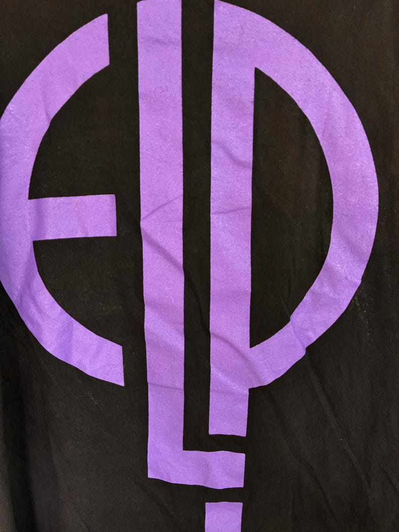 May include: Black t-shirt with a large, purple graphic design. The graphic is a monogram or logo, with the letters "E", "L", and "P" in a bold, sans-serif font. The design is centrally placed on the shirt.