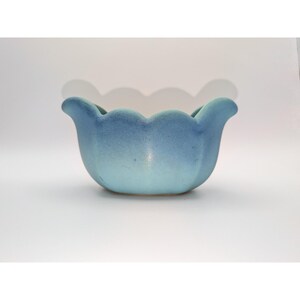 May include: A blue ceramic bowl with a scalloped rim. The bowl has a gradient of blue hues, transitioning from a lighter shade at the base to a darker shade at the top. The bowl is likely for decorative use.