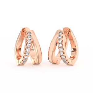 May include: A pair of rose gold hoop earrings. Each earring features a double hoop design, with one hoop adorned with a row of small, sparkling white gemstones. The earrings are displayed against a white background.