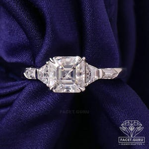 Puede incluir: Un anillo de compromiso de platino con un diamante central de talla cuadrada grande y dos piedras laterales más pequeñas, de talla trapezoidal. El anillo está sobre una tela azul oscuro. El texto "Facet.Guru" es visible.