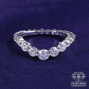May include: A silver-toned curved band ring featuring a row of round, clear, faceted stones set along the top edge. The ring has a V-shaped contour and a polished metallic finish. The text FACET.GURU HANDCRAFTED is visible in the bottom right corner.