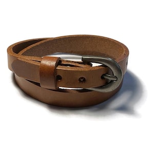 May include: A brown leather belt with a silver buckle. The belt is wrapped twice around itself.