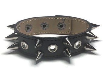 May include: Black leather bracelet with silver metal spikes and eyelets.