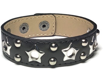 Puede incluir: Pulsera de cuero negro con detalles de estrellas plateadas y tachuelas.