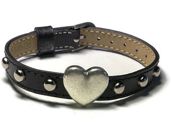 May include: A black leather bracelet with silver studs and a silver heart charm.