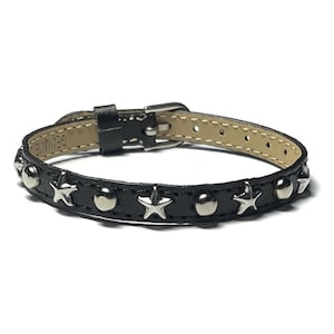 May include: Black leather bracelet with silver star and stud accents. The bracelet has a buckle closure.