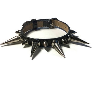 May include: Black leather bracelet with silver spikes. The bracelet is adjustable and has a buckle closure.