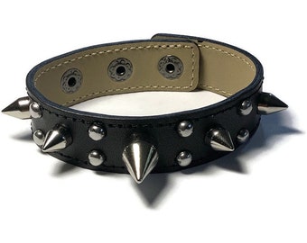 May include: Black leather bracelet with silver studs and spikes.