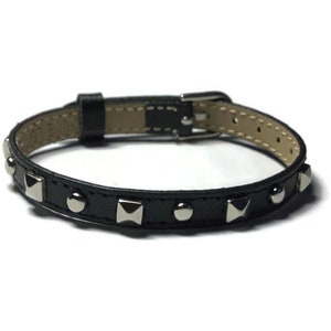 May include: A black leather bracelet with silver studs. The bracelet has a buckle closure.