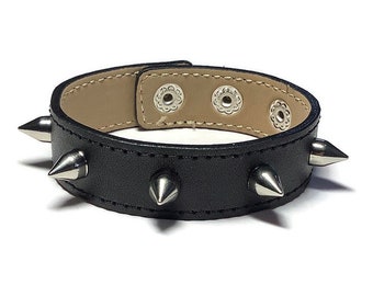 May include: Black leather bracelet with silver metal spikes. The bracelet has three silver metal snaps.