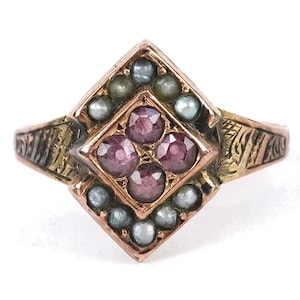 May include: A vintage gold ring with a diamond-shaped center. The center features four deep red gemstones surrounded by small, light-colored pearls. The ring's band has intricate etched designs and a warm, antique finish.