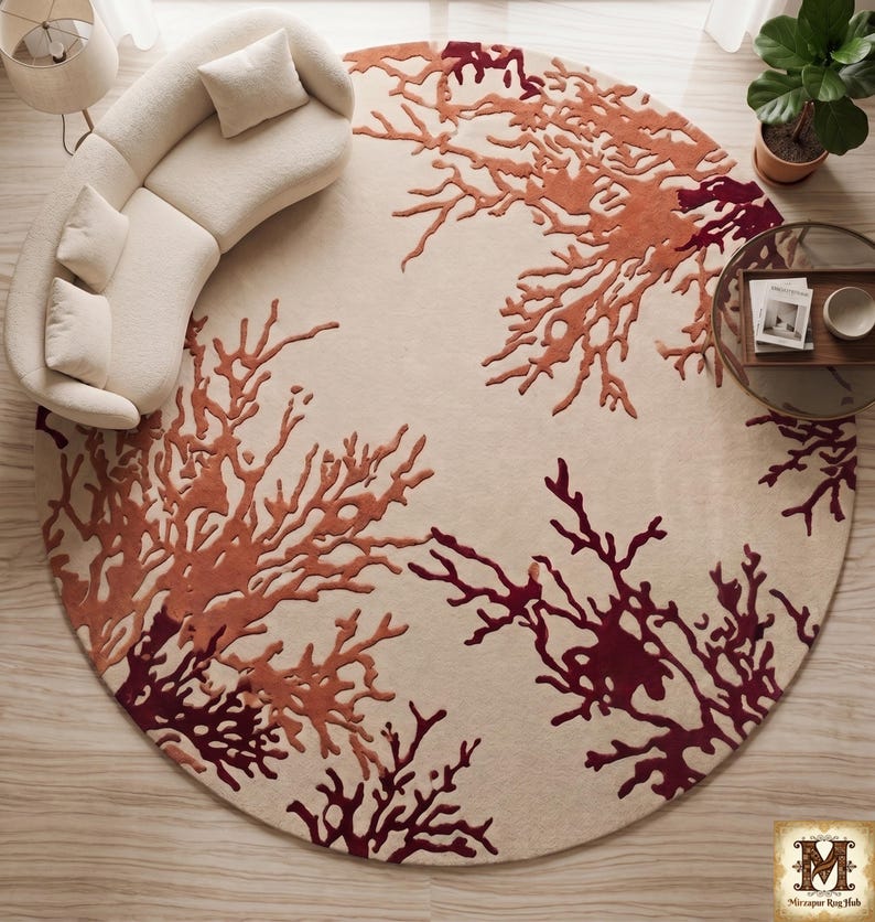 Puede incluir: Una alfombra circular grande con fondo color crema y un patr&oacute;n texturizado en relieve de formas de coral ramificadas en tonos naranja quemado y granate profundo. El dise&ntilde;o se extiende por toda la superficie con un motivo org&aacute;nico.