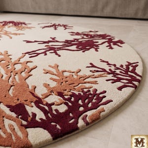 Puede incluir: Una alfombra circular con fondo color crema y un patr&oacute;n texturizado en relieve de ramas similares a corales en tonos burdeos intenso y naranja apagado. El dise&ntilde;o se distribuye por toda la superficie de esta pieza textil redonda.