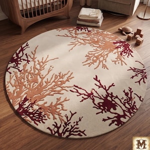 Puede incluir: Una alfombra redonda con fondo color crema y un patr&oacute;n repetitivo de ramas similares al coral en tonos burdeos intenso y naranja apagado. El dise&ntilde;o es sim&eacute;trico, con formas org&aacute;nicas ramificadas que se extienden desde los bordes.