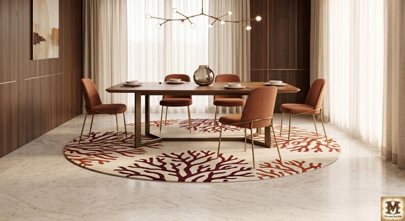 Puede incluir: Una mesa de comedor rectangular de madera con base de metal oscuro, rodeada de seis sillas tapizadas en tela naranja quemado con patas finas de tono dorado, sobre una gran alfombra circular con un patr&oacute;n de coral rojo sobre fondo crema.