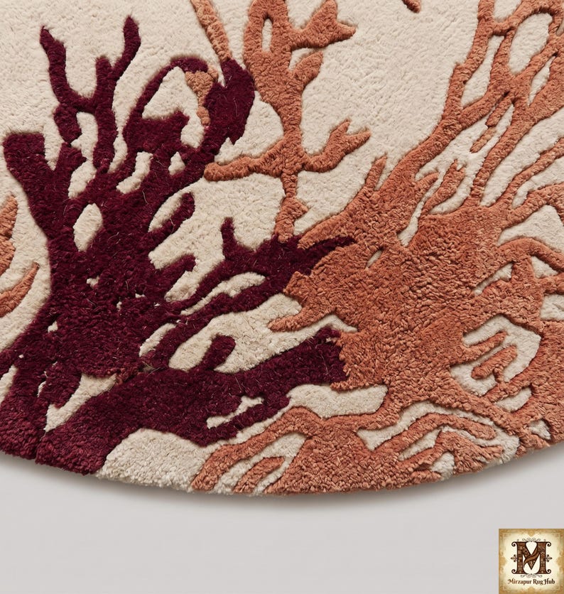 Puede incluir: Una alfombra circular con una base de color crema y un dise&ntilde;o copetudo en relieve de estructuras ramificadas similares al coral en tonos burdeos intenso y naranja terracota apagado. La textura es densa y afelpada, creando contraste.