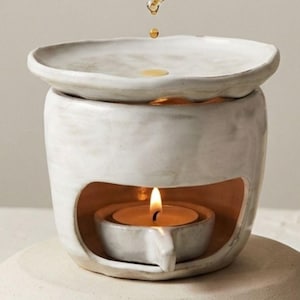 May include: A white ceramic mug with a black handle and the text "But First, Coffee" in a black, handwritten-style font. The mug is on a white surface.