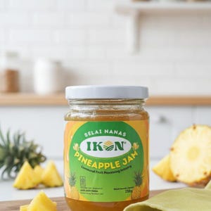 May include: A jar of Ikon Pineapple Jam with a white lid, set on a wooden cutting board with fresh pineapple chunks. The label features text in green and yellow, with the words "Pineapple Jam".