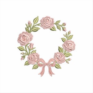 May include: Embroidered wreath design featuring pink roses, green leaves, and a pink bow. The floral arrangement is circular, with detailed stitching creating a textured appearance. The design is set against a white background.