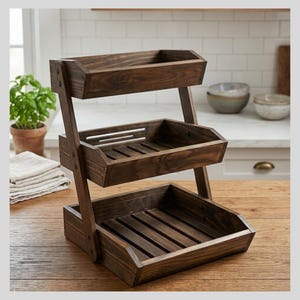 May include: A three-tiered wooden serving stand with a dark brown finish. The stand features three rectangular trays with slatted bottoms, supported by angled side supports. The stand is designed for displaying or serving items.