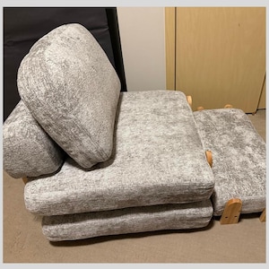 May include: A set of light gray upholstered cushions with wooden frames. The cushions are stacked and arranged, showcasing a textured fabric. The design suggests a modular seating arrangement, suitable for a living room or lounge area.