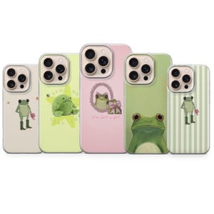 May include: Five phone cases with frog designs. The cases feature various frog illustrations, including a frog with a flower, a plush frog, and a frog with a bow. The cases are in shades of green, pink, and cream.