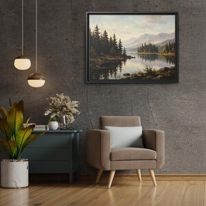 May include: A framed landscape painting depicting a calm lake surrounded by dense evergreen trees and distant mountains under a soft, cloudy sky. The artwork features muted earth tones, deep greens, and reflective water, presented in a black frame.