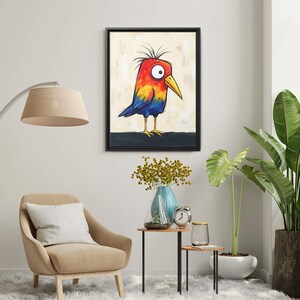 May include: A framed wall art print featuring a cartoon bird with a bright red head, yellow chest, and blue wings. The bird has a large white eye with a black pupil, a yellow beak, and spiky feathers on top of its head. It stands on a dark horizontal line against a light, textured background.
