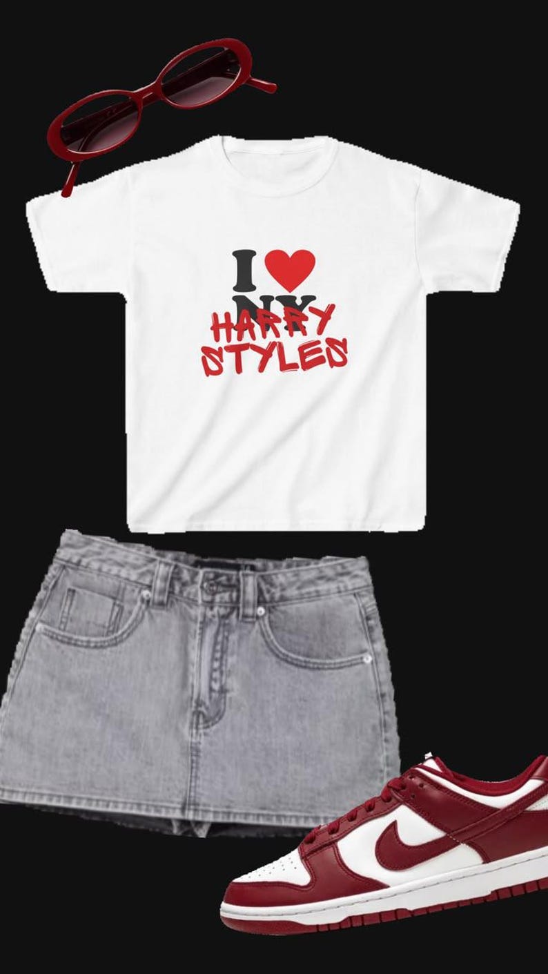 May include: A white short-sleeve t-shirt with the text I heart NY HARRY STYLES in black and red, a light wash denim mini skirt, red oval-frame sunglasses, and low-top sneakers in a two-tone white and dark red colorway with a side swoosh.