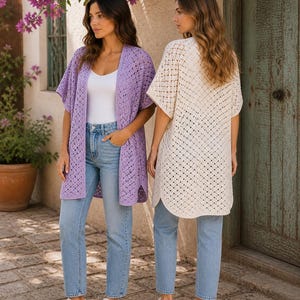May include: Two women wearing open-front crochet cardigans. One is a light purple color, the other is off-white. Both are paired with light blue jeans and white sneakers. The background includes a stone walkway, a wooden door, and flowering plants.