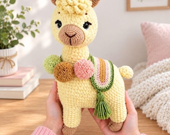 May include: A pale yellow crocheted llama plush toy featuring a textured head, dark brown nose, and black eyes. It is adorned with three pom-poms in light green, brown, and pink, and a decorative saddle blanket with green, pink, and tan stripes.