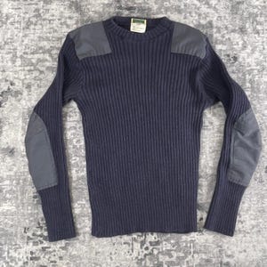 May include: Navy blue ribbed knit sweater with reinforced patches on the shoulders and elbows. The long-sleeved sweater has a crew neck and a tag at the back of the neck. The patches are a contrasting gray color.