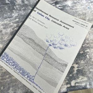 May include: A white softcover report titled Geothermal Resource Assessment of Cañon City, Colorado Area by Ted G. Zacharakis and Richard Howard Pearl. The cover features a black and blue stippled geological cross-section diagram and text.