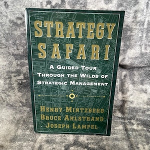 May include: A hardcover book titled "Strategy Safari" with a dark green cover. The title is in large gold letters. The cover features a map design with street names. The authors' names are listed at the bottom.