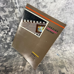 May include: A brown Zilog 1982/83 Data Book with a graphic of a circuit board and a world map. The cover features a thin orange horizontal line, the text 1982/83 Data Book, and the Zilog logo with the slogan Pioneering the Microworld in yellow.