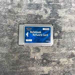 May include: A silver rectangular Belkin Notebook Network Card with a blue label featuring white text that reads Notebook Network Card, 16 PCMCIA, and F505020. The card includes a white arrow icon pointing upward with the text insert this side up.