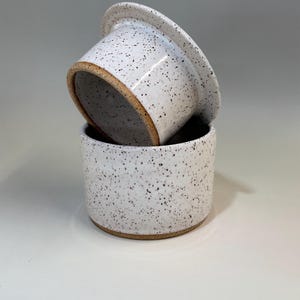 Pu&ograve; includere: Burriera in ceramica in due pezzi. Il piatto &egrave; bianco con macchie marroni e un bordo marrone naturale. Il coperchio &egrave; leggermente inclinato, rivelando l'interno del piatto.