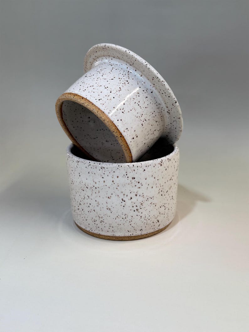 Pu&ograve; includere: Burriera in ceramica in due pezzi. Il piatto &egrave; bianco con macchie marroni e un bordo marrone naturale. Il coperchio &egrave; leggermente inclinato, rivelando l'interno del piatto.