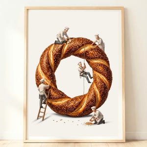 May include: A framed art print featuring a large, golden-brown, sesame-crusted bagel or simit. Five miniature figures dressed in white chef uniforms and hats are interacting with the bread, using a ladder, ropes, and tools to work on it.