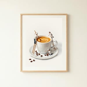 May include: A framed print depicts a whimsical scene of miniature chefs preparing coffee in an oversized white mug. The coffee is swirled, and the cup sits on a saucer with scattered coffee beans. The chefs use ladders and spoons.
