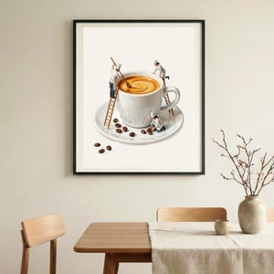 May include: A framed wall art print featuring a large white coffee cup on a saucer. Miniature figures dressed as chefs are climbing wooden ladders to stir the coffee and arrange dark brown coffee beans on the saucer and surrounding surface.