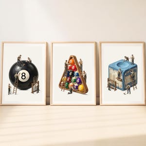 May include: Three framed art prints featuring miniature workers interacting with billiards equipment. The first shows workers on a black eight ball, the second a triangular rack of colourful numbered balls, and the third a blue cube of billiard chalk.