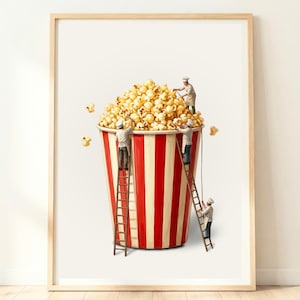 Peut inclure: Impression encadrée d'un grand seau de pop-corn à rayures rouges et blanches, débordant de pop-corn. De petits chefs sur des échelles semblent s'occuper du pop-corn. Le fond est blanc.