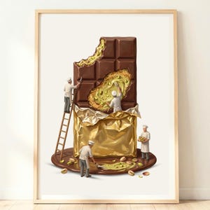 May include: A framed art print depicting miniature chefs in white uniforms working on a large chocolate bar wrapped in gold foil. The chocolate is filled with shredded pastry and green pistachios, with scattered nuts on the base surface.