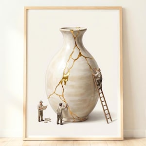 May include: A framed wall art print depicting a large, off-white ceramic vase with prominent cracks filled with gold lacquer. Three miniature figures in work clothes are shown repairing the vase, with one figure standing on a wooden ladder.
