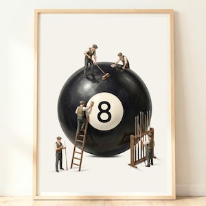 Puede incluir: Una lámina enmarcada que muestra una gran bola de billar negra número ocho siendo limpiada por cuatro figuras en miniatura con ropa vintage. Una figura está sobre una escalera de madera, otra usa un cepillo y hay un soporte con tacos de billar.