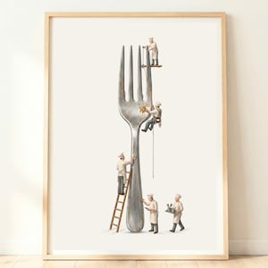 May include: A framed wall art print featuring a giant silver fork being cleaned by five miniature chefs in white uniforms. One chef stands on a wooden ladder, another rappels down the tines, while others work on the surface and carry tools.