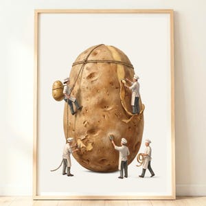 Könnte beinhalten: Ein gerahmter Kunstdruck, der eine große braune Kartoffel zeigt, die von fünf Miniaturfiguren in weißen Kochuniformen und Mützen geschält und bearbeitet wird. Die Figuren verwenden Seile, Schaber und Bürsten, um die Oberfläche zu bearbeiten.