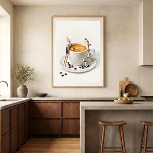 May include: A framed print depicts a whimsical scene of miniature chefs working on a giant cup of coffee. The coffee is in a white mug on a saucer, surrounded by coffee beans. The print is in a light brown wooden frame, set against a neutral-toned kitchen.